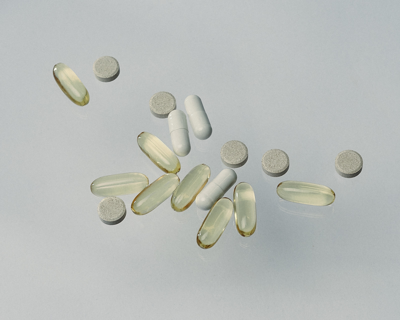 Assorted capsules and tablets on a pale surface