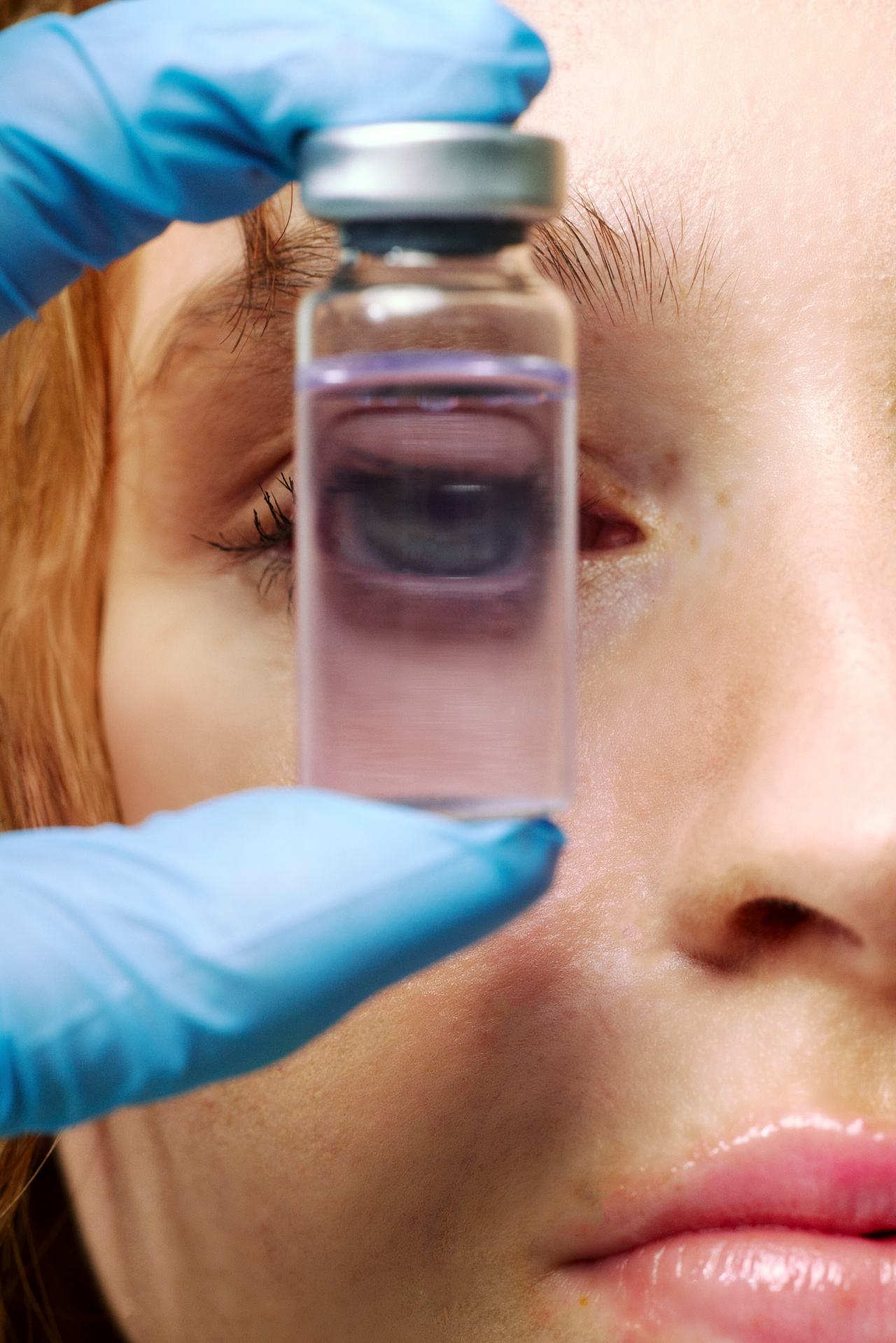 A close-up of a person examining a small vial of clear liquid